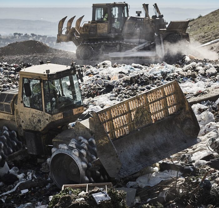 heavy equipment moving garbage in a landfill