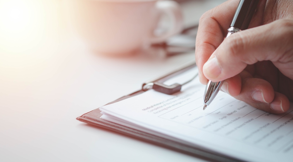 person writing on a paper document