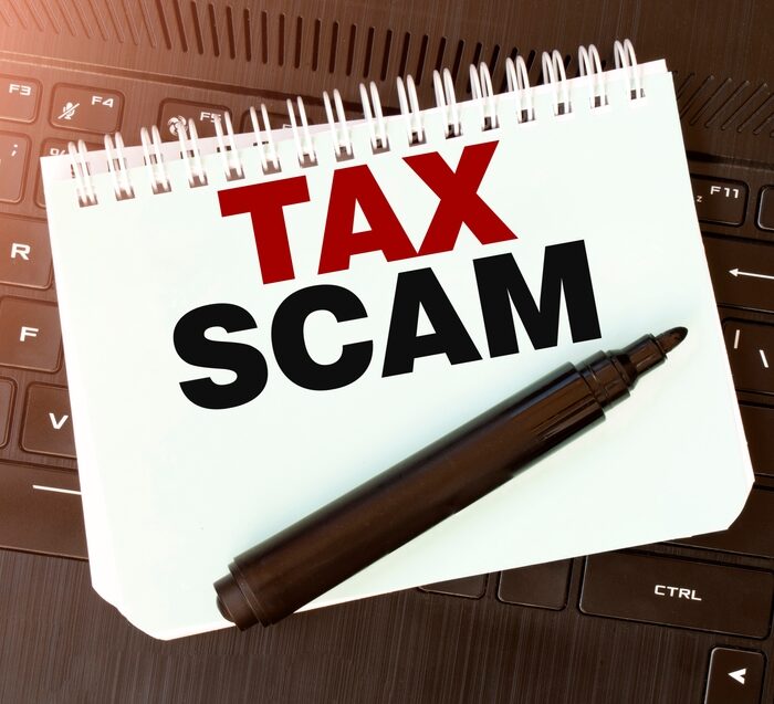 "Tax Scam" on a notepad with a felt pen
