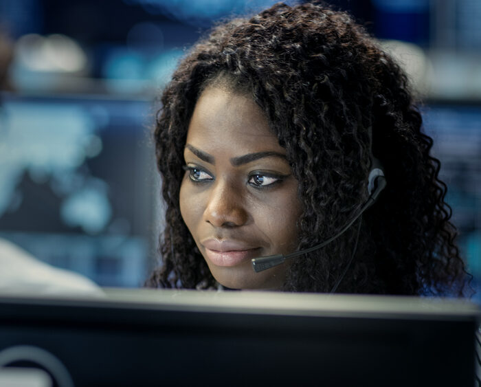 woman with a headset looking at a computer screen