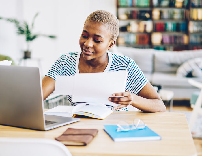 woman looking a papers and a laptop