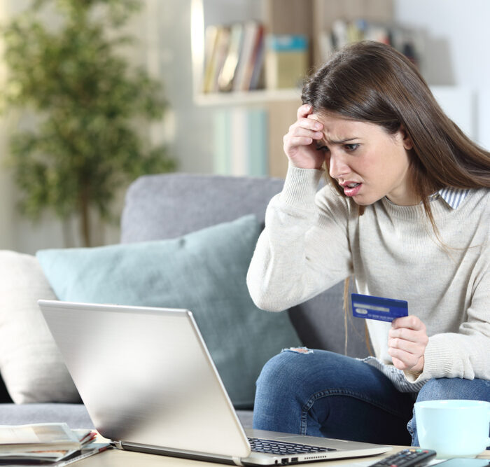 concerned woman holding a credit card looking at a laptop