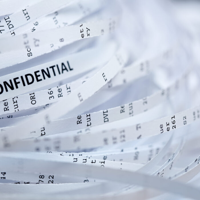 The word "CONFIDENTIAL" is shown on a single small strip of paper amongst a pile of shredded documents.