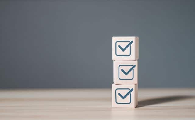 Checklist survey concept. Man hand holding wooden cube with checklist icon