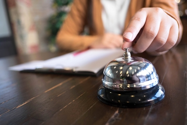 Women call hotel reception with finger push a bell in lobby hotel