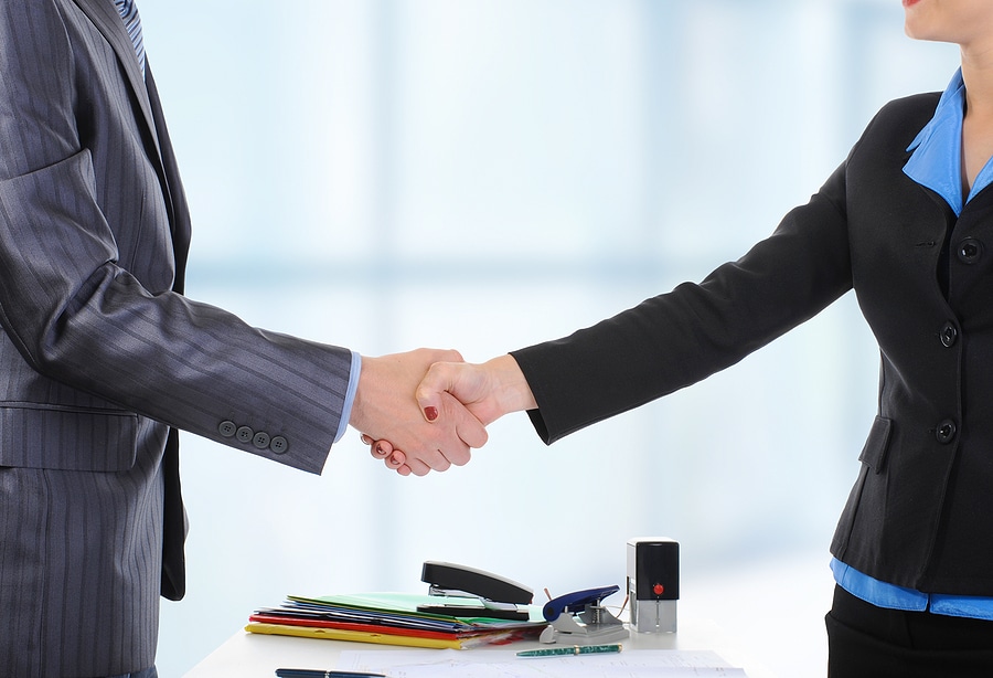 Business professionals shaking hands over documents.